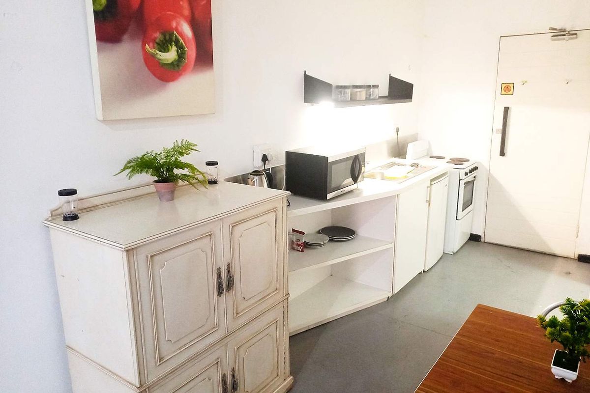 A functional kitchenette featuring built-in cabinetry, a stove, and a sink, providing essential cooking and preparation space within the apartment.