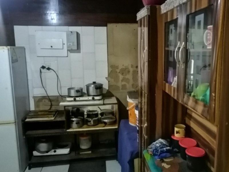 A dated kitchen area featuring built-in cabinetry and tiled splashbacks, currently showing signs of wear and requiring maintenance or renovation.