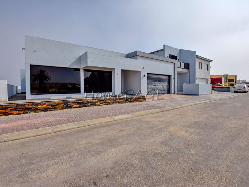 Modern contemporary house exterior featuring a paved driveway, stone cladding accents, and a secure garage entrance.