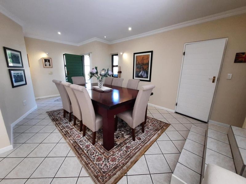 A well-maintained dining room featuring neutral wall tones, tiled flooring, recessed lighting, and decorative cornicing, providing a bright and functional space for meals.