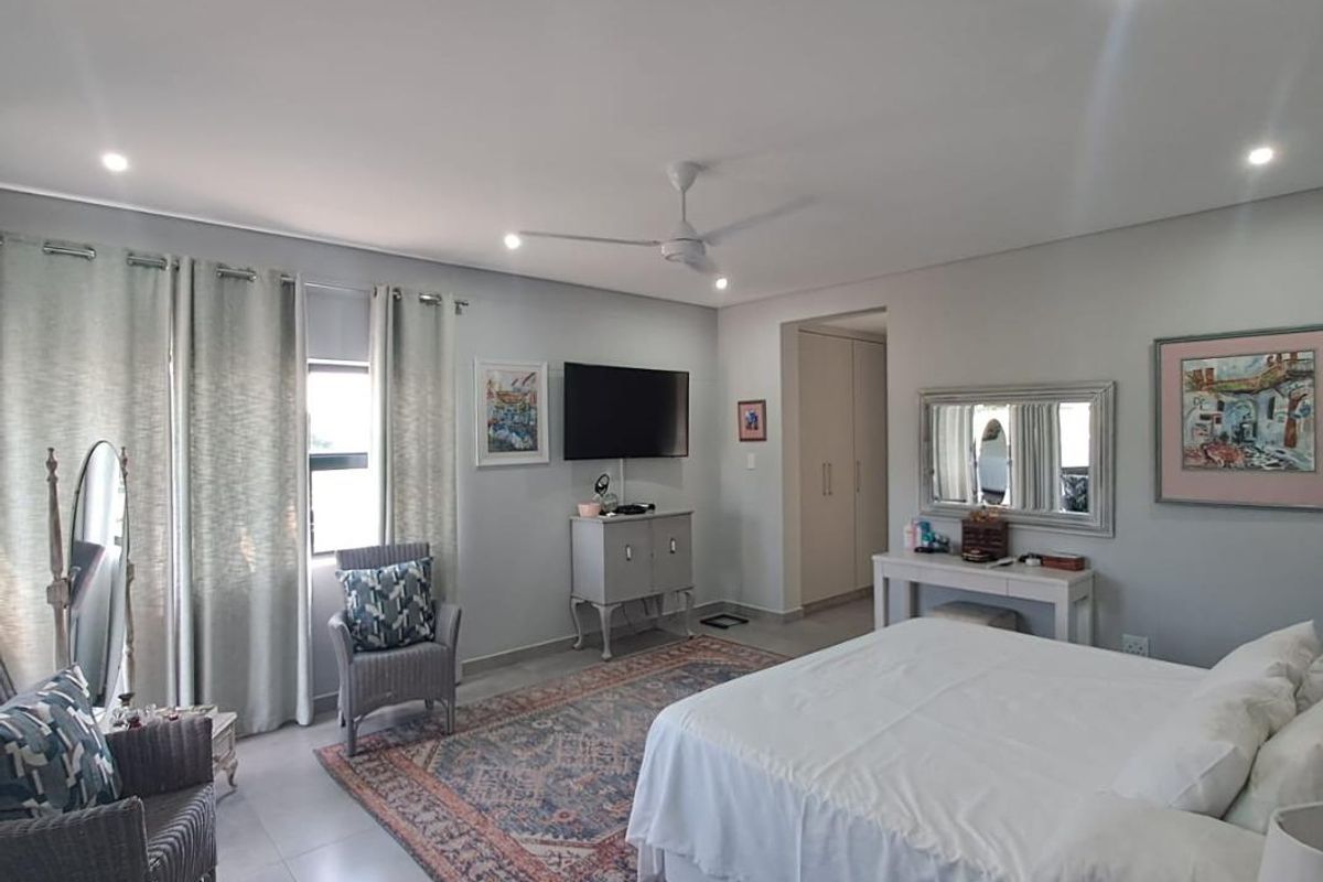 Spacious bedroom featuring neutral tiled flooring, recessed downlighting, a ceiling fan, and built-in storage cupboards.