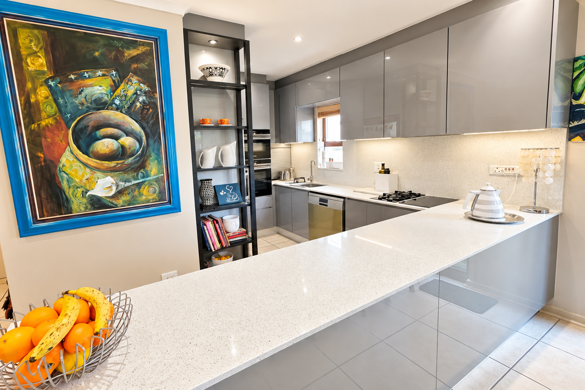 Modern kitchen featuring sleek grey cabinetry, quartz countertops, integrated appliances, and a functional breakfast bar layout with under-cabinet lighting.