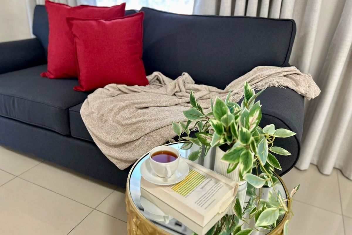 A cozy living room area featuring neutral floor tiles and floor-to-ceiling curtains, creating a comfortable and inviting atmosphere.