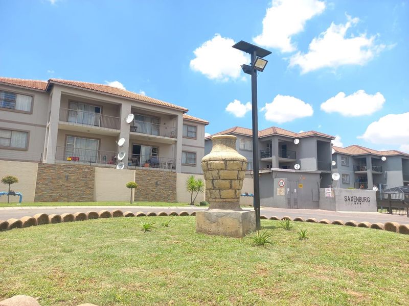 Front view of the Saxenburg townhouse complex featuring multi-story residential buildings with balconies, tiled roofs, and landscaped common areas.