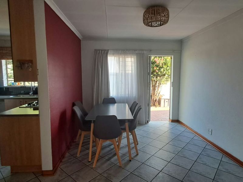 Open-plan dining area adjacent to a functional kitchen, featuring tiled flooring and direct access to the outdoor patio area.
