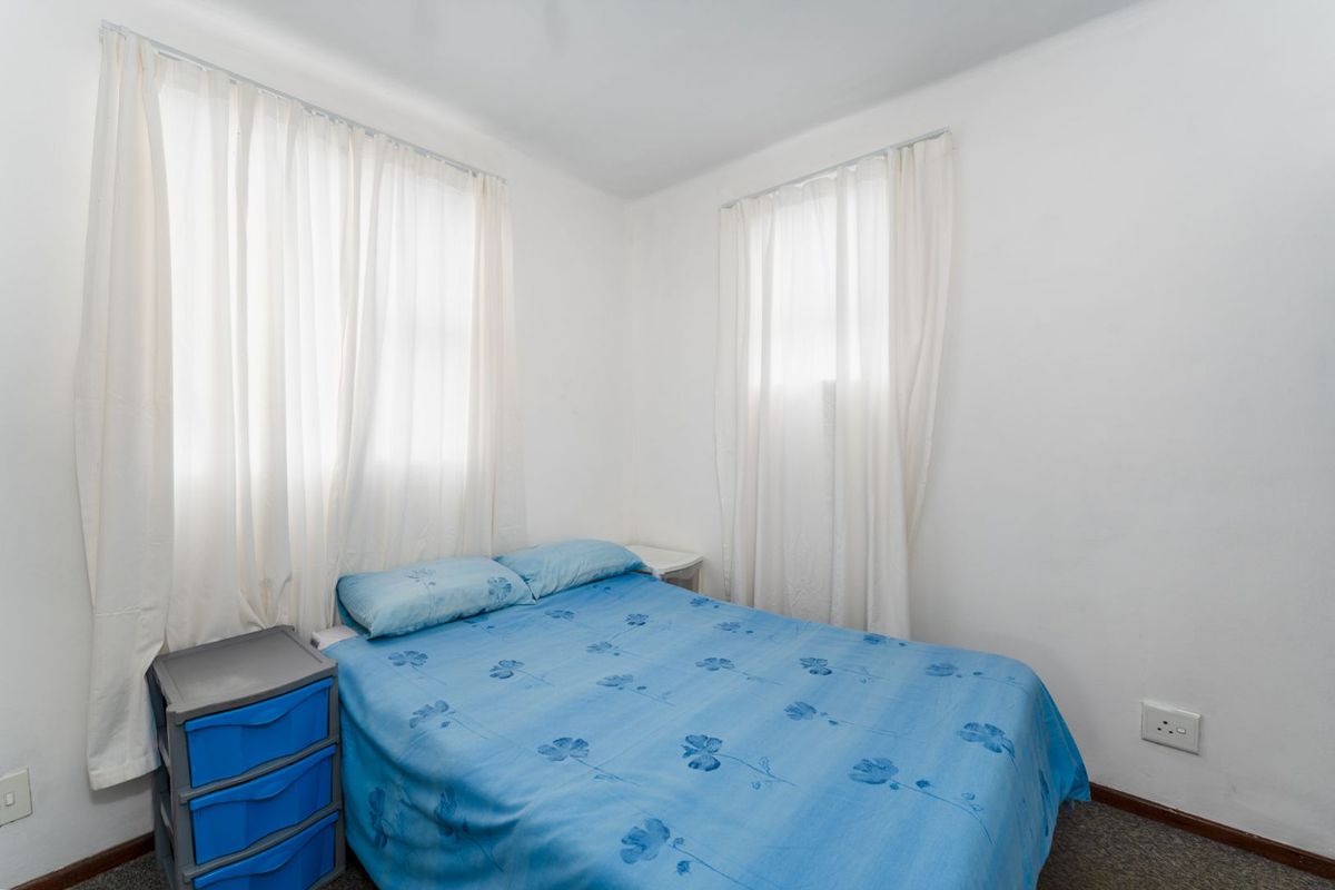 A functional bedroom featuring carpeted flooring and dual windows, providing a neutral space ready for personalization.