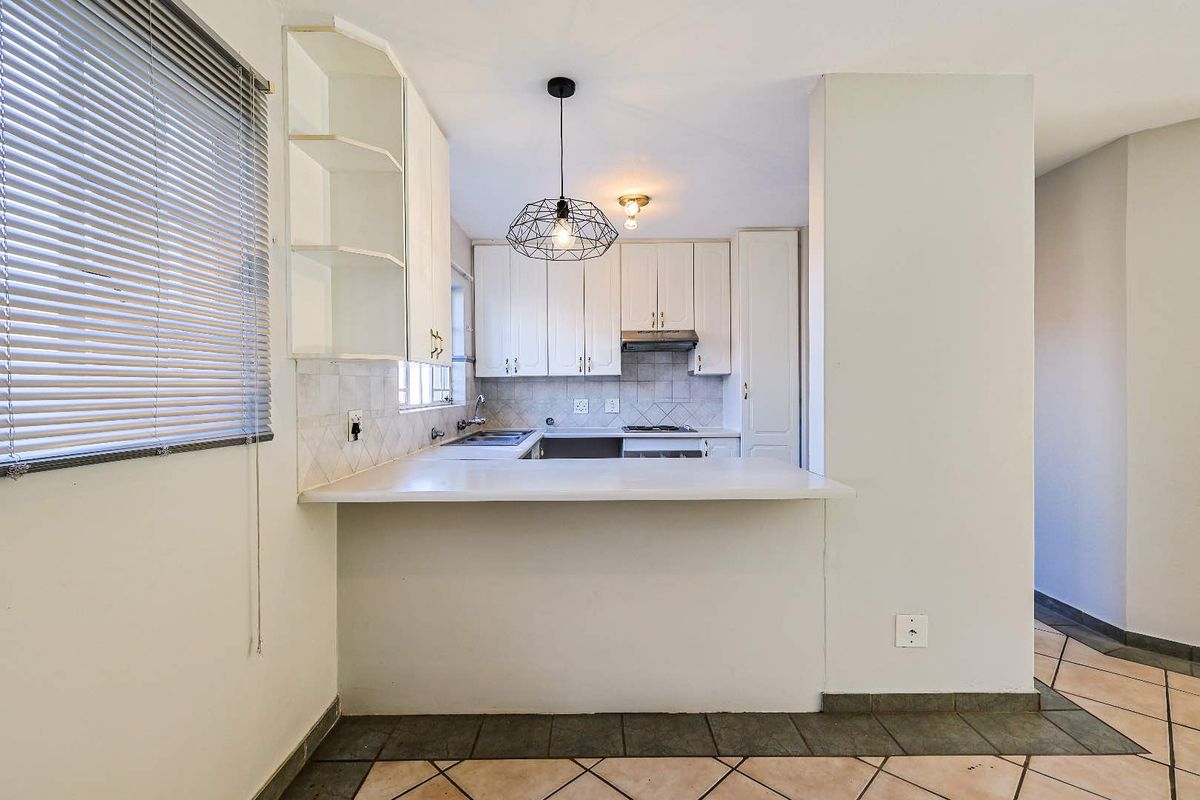 A functional kitchen featuring white cabinetry, a breakfast bar counter, tiled backsplash, and integrated stove with extractor fan.