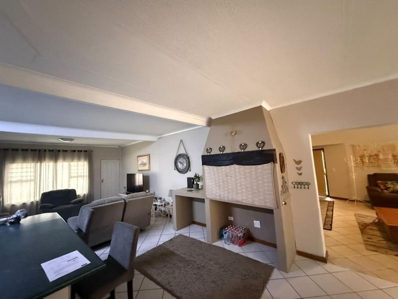 Open plan living area featuring tiled flooring, a central built-in fireplace, and coved ceilings, connecting to adjacent living spaces.