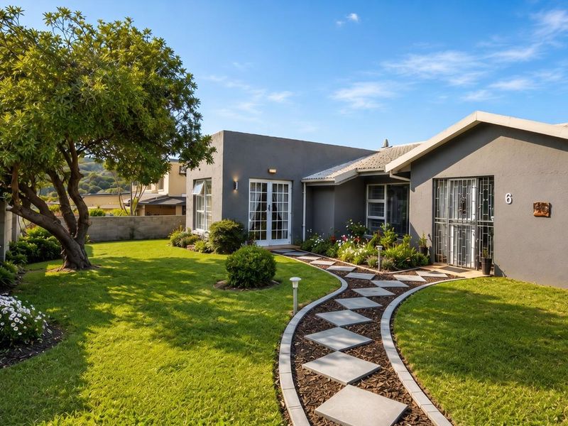 A well-maintained front exterior featuring a landscaped garden, a decorative paved walkway, and a modern grey facade with secure entry points.