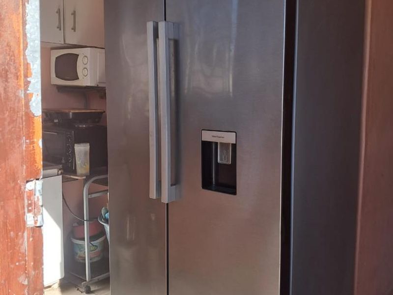A compact kitchen area featuring tiled flooring and built-in cabinetry, showing signs of wear on the surrounding door frame.