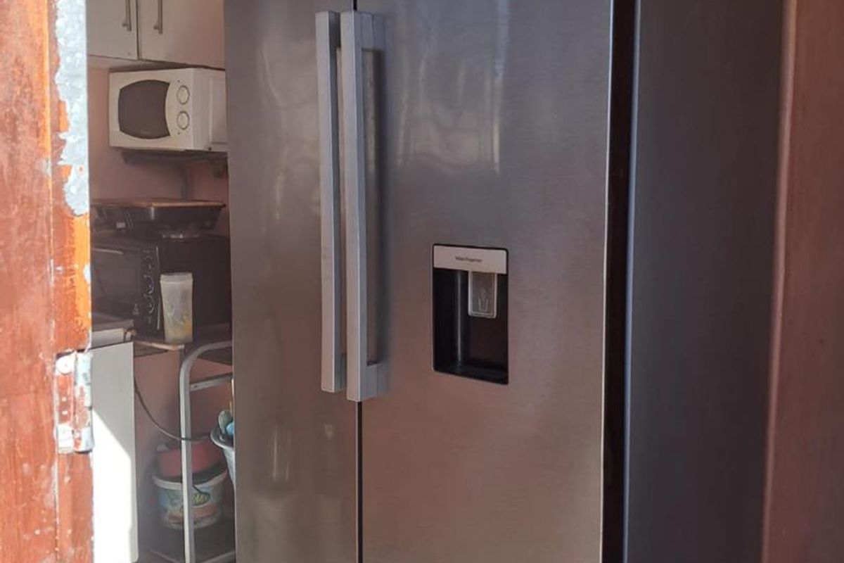 A compact kitchen area featuring tiled flooring and built-in cabinetry, showing signs of wear on the surrounding door frame.