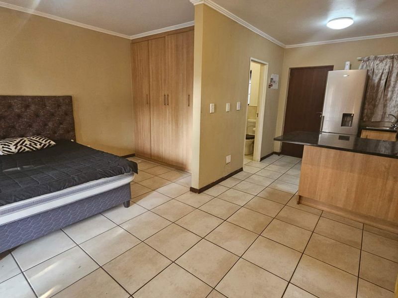 Open-plan studio apartment featuring a combined bedroom and kitchen area with built-in cupboards, granite countertops, and tiled flooring throughout.