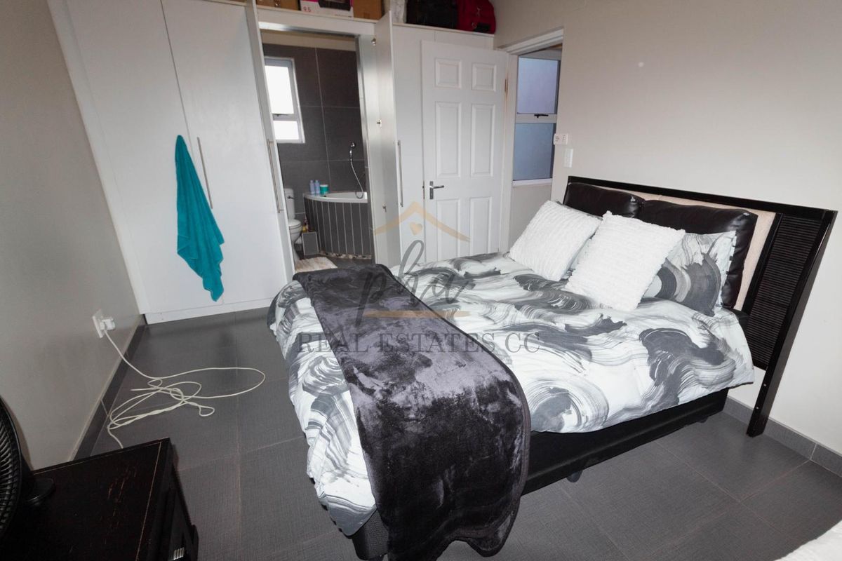 A bedroom featuring built-in cupboards and an en-suite bathroom with tiled flooring throughout.
