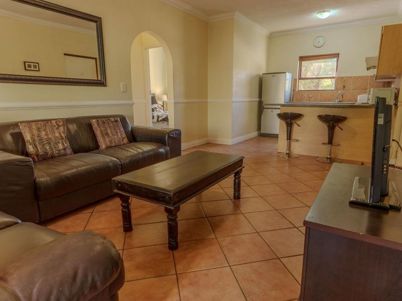 Open-plan living area featuring tiled flooring, a breakfast bar, and a functional kitchen layout with direct access to the bedroom.