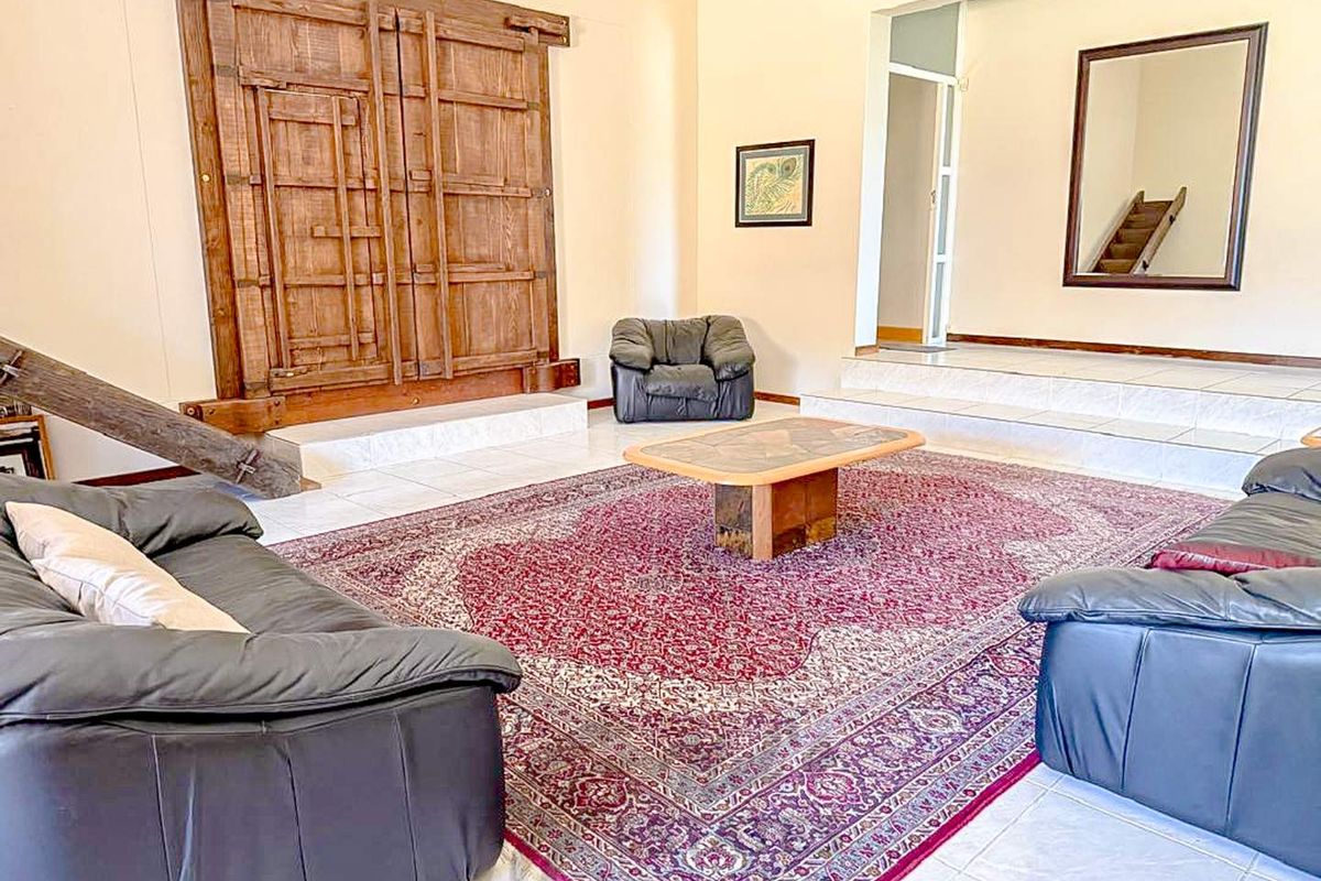 Spacious living room featuring tiled flooring, a raised platform area, and a large decorative wooden wall feature.