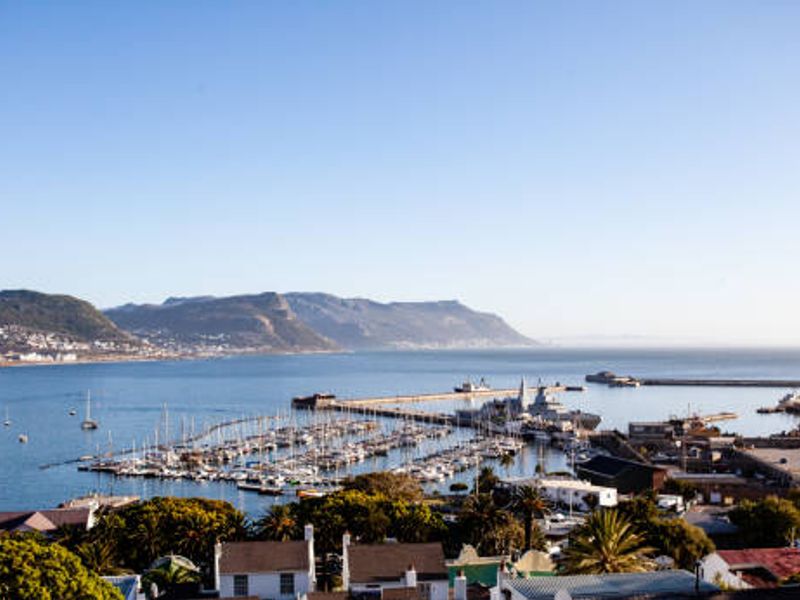 A scenic elevated view overlooking the harbour, marina, and surrounding coastal mountains.