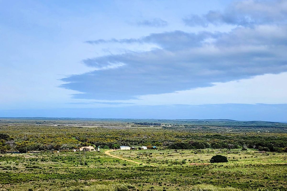 An expansive aerial view of the rural farm property, showcasing the surrounding landscape, natural vegetation, and existing farm structures.