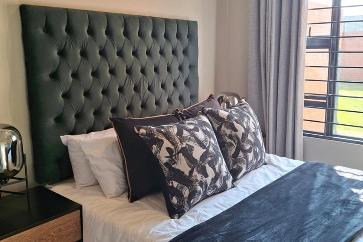 A well-maintained bedroom featuring a window with security bars and neutral wall finishes.