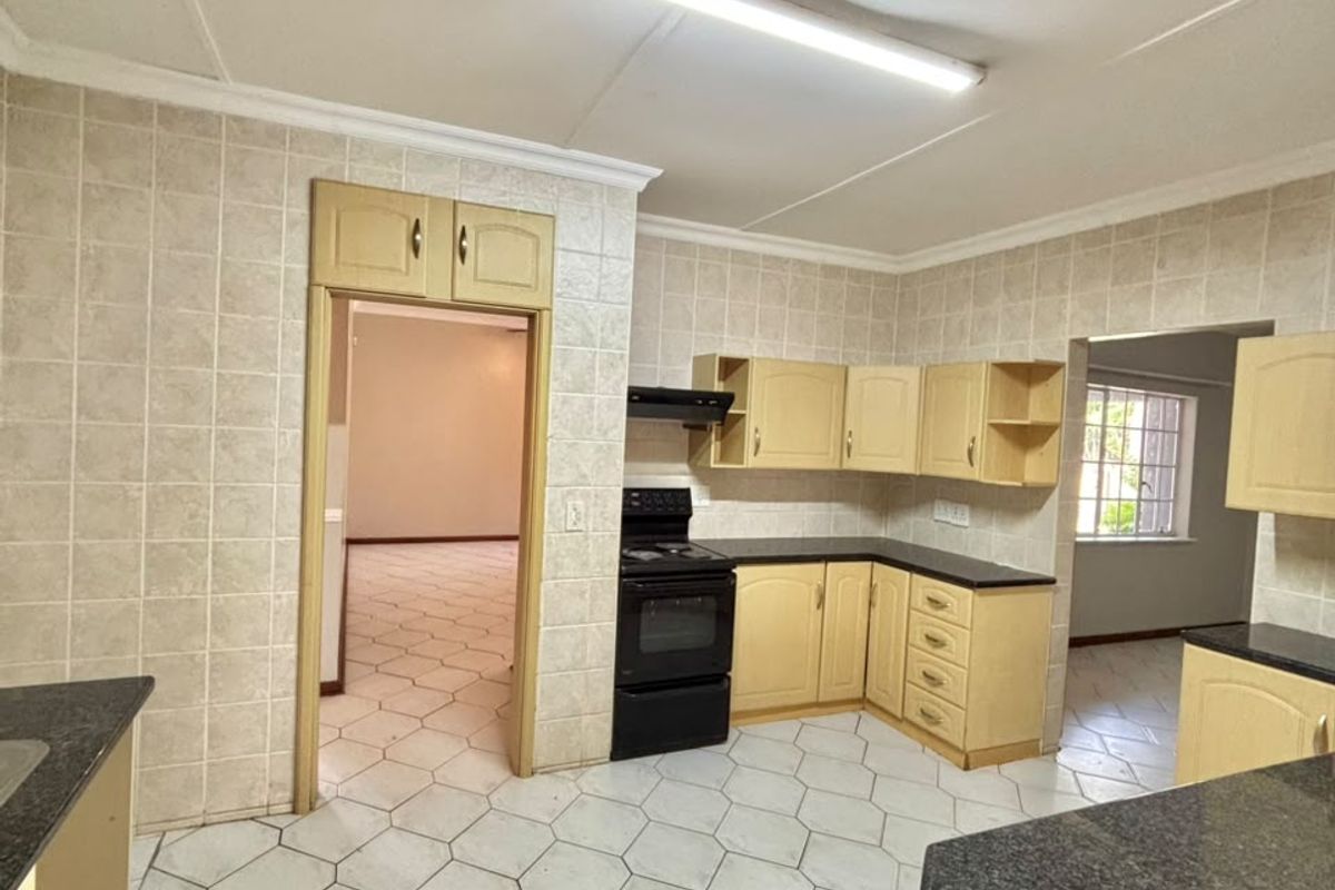 A functional kitchen featuring built-in cabinetry, laminate countertops, a freestanding stove with extractor fan, and tiled flooring throughout.
