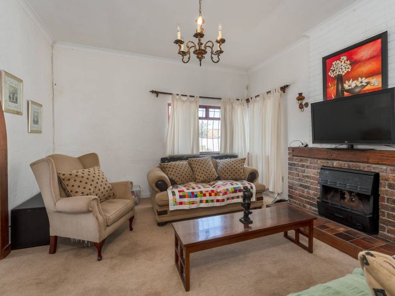 A living room featuring a brick fireplace with a mantel, coving, and an arched doorway, finished with carpeted flooring.