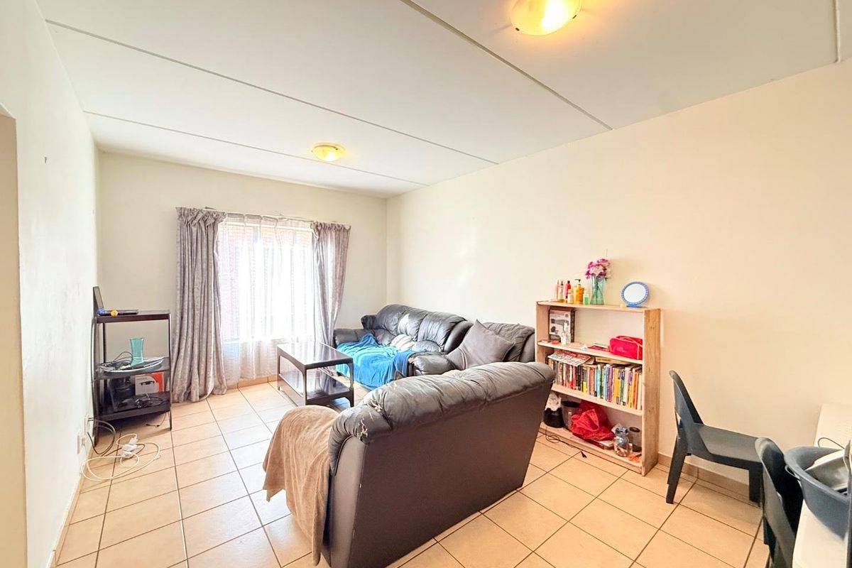 A living room featuring tiled flooring and ceiling panels, offering a functional space with natural light from the window.