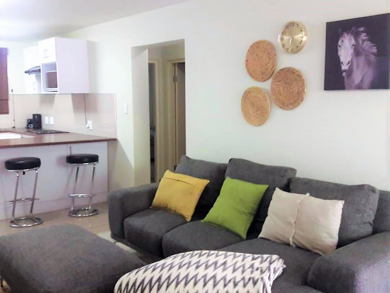 Open plan living area featuring a functional kitchen with island and tiled flooring, seamlessly connected to the lounge space.