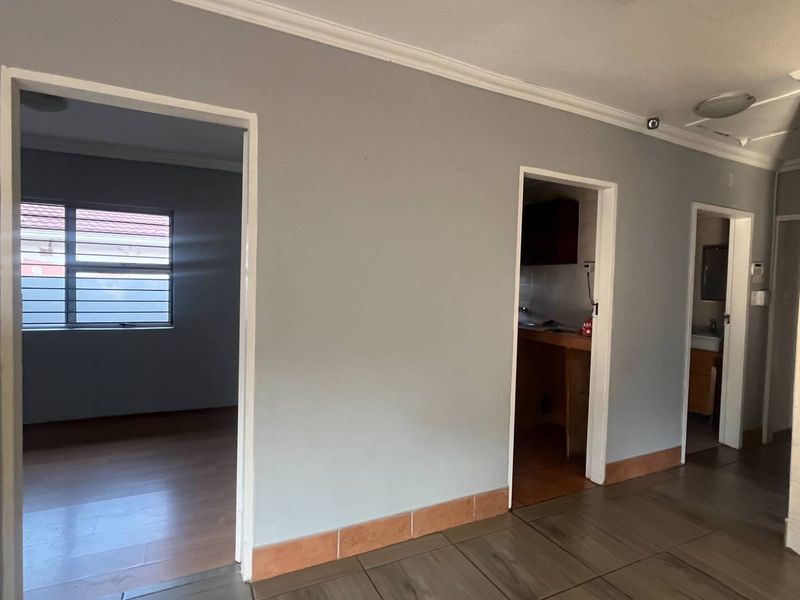 A neutral hallway featuring tiled flooring and coving, providing access to multiple rooms within the home.