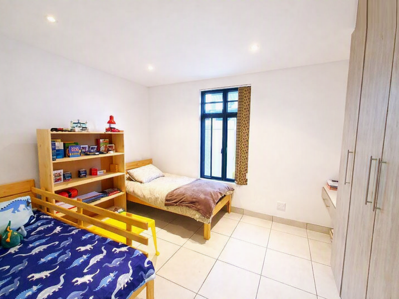 A well-lit bedroom featuring tiled flooring, recessed downlighting, and ample built-in cupboard storage space.