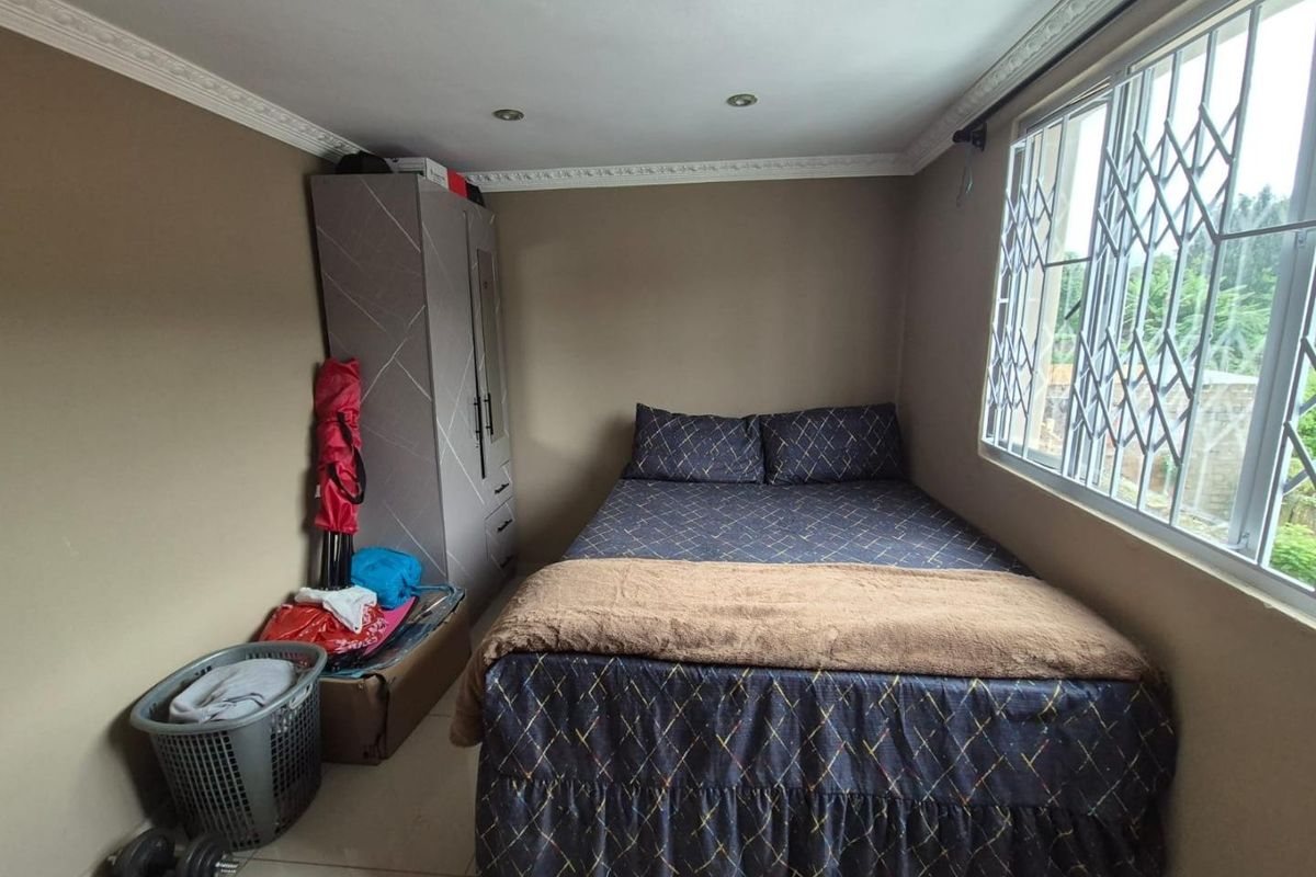 A compact bedroom featuring tiled flooring, crown molding, recessed lighting, and large windows fitted with security bars.
