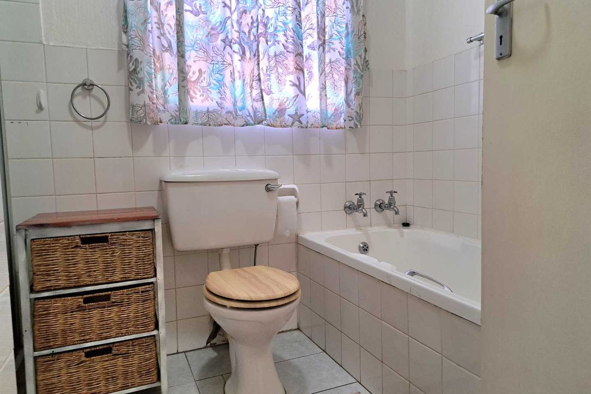 A functional bathroom featuring a standard bathtub, toilet, and tiled wall finishes.