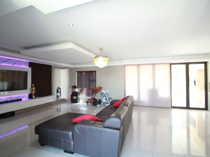 Modern living room featuring a sleek built-in media wall with integrated LED lighting, recessed ceiling details, and large sliding glass doors leading outdoors.