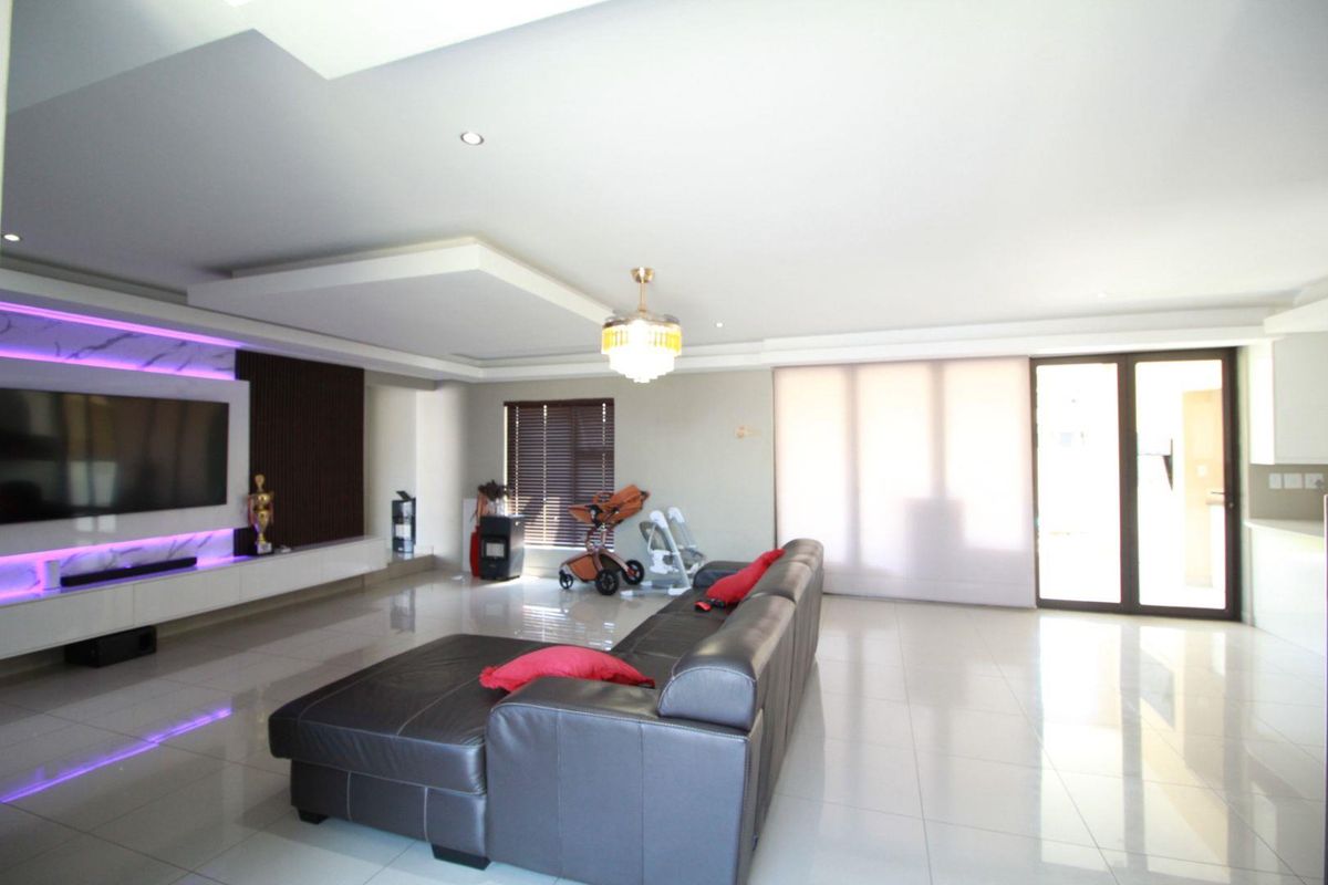 Modern living room featuring a sleek built-in media wall with integrated LED lighting, recessed ceiling details, and large sliding glass doors leading outdoors.
