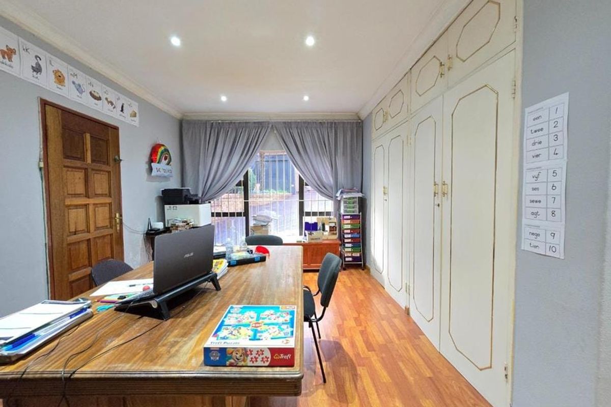 A bedroom featuring laminate flooring, recessed downlighting, and extensive built-in cupboard storage along one wall.