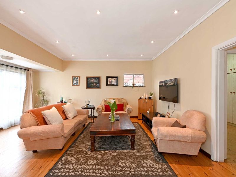 A well-lit living room featuring polished hardwood flooring, recessed downlighting, and a sliding glass door providing natural light.