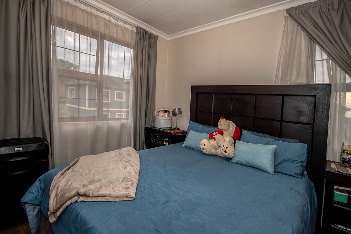 A cozy bedroom featuring a large window with curtains and neutral wall finishes.