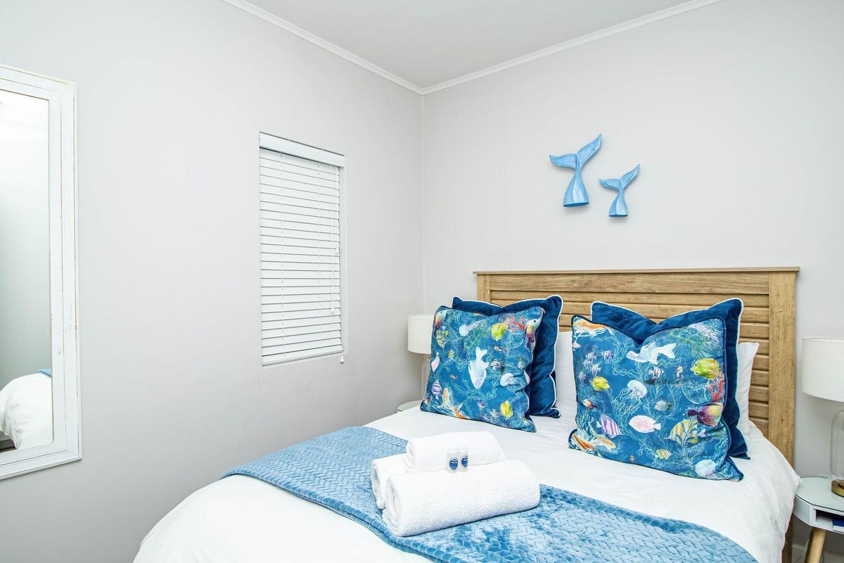 A well-maintained bedroom featuring neutral wall finishes, a built-in headboard, and a window fitted with white venetian blinds.