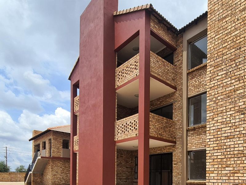 Exterior view of a modern apartment building featuring face brick construction, multi-level balconies, and a tiled roof.