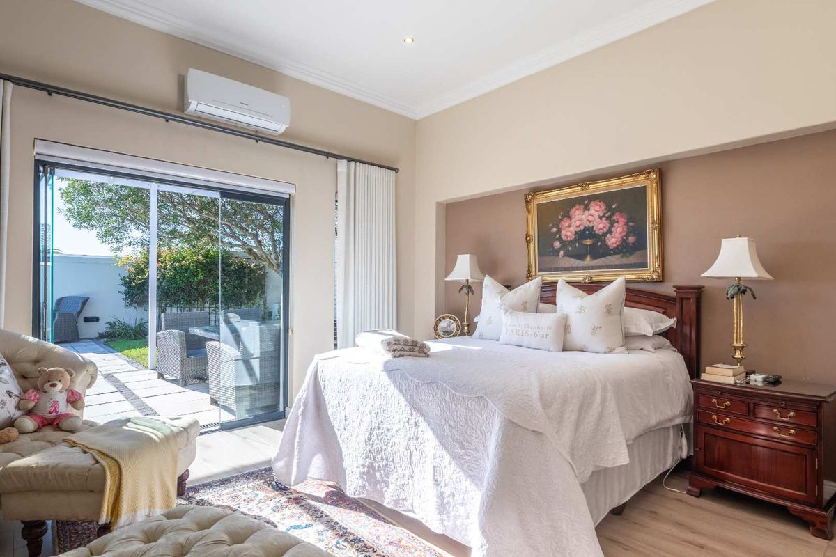 Spacious bedroom featuring laminate flooring, recessed lighting, a split-system air conditioner, and direct access to an outdoor patio through sliding glass doors.