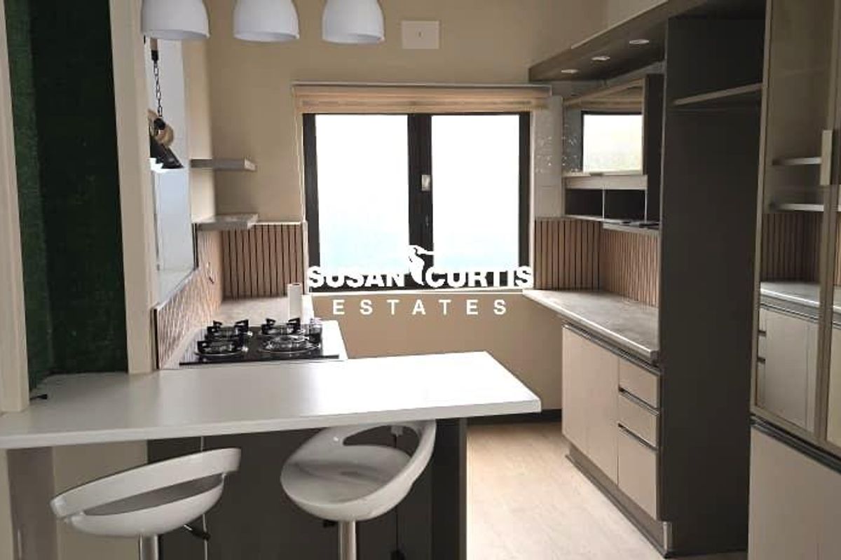 Modern kitchen featuring built-in cabinetry, a breakfast bar, integrated gas hob, and neutral finishes, offering a functional and contemporary cooking space.