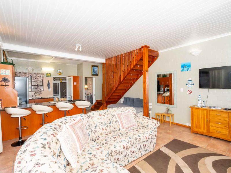 Open-plan living area featuring a kitchen with island, tiled flooring, and a timber staircase leading to the upper level.
