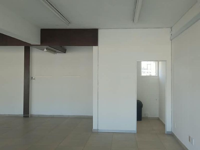 A spacious, empty open-plan retail area featuring tiled flooring, structural columns, and neutral white walls, suitable for various commercial business layouts.