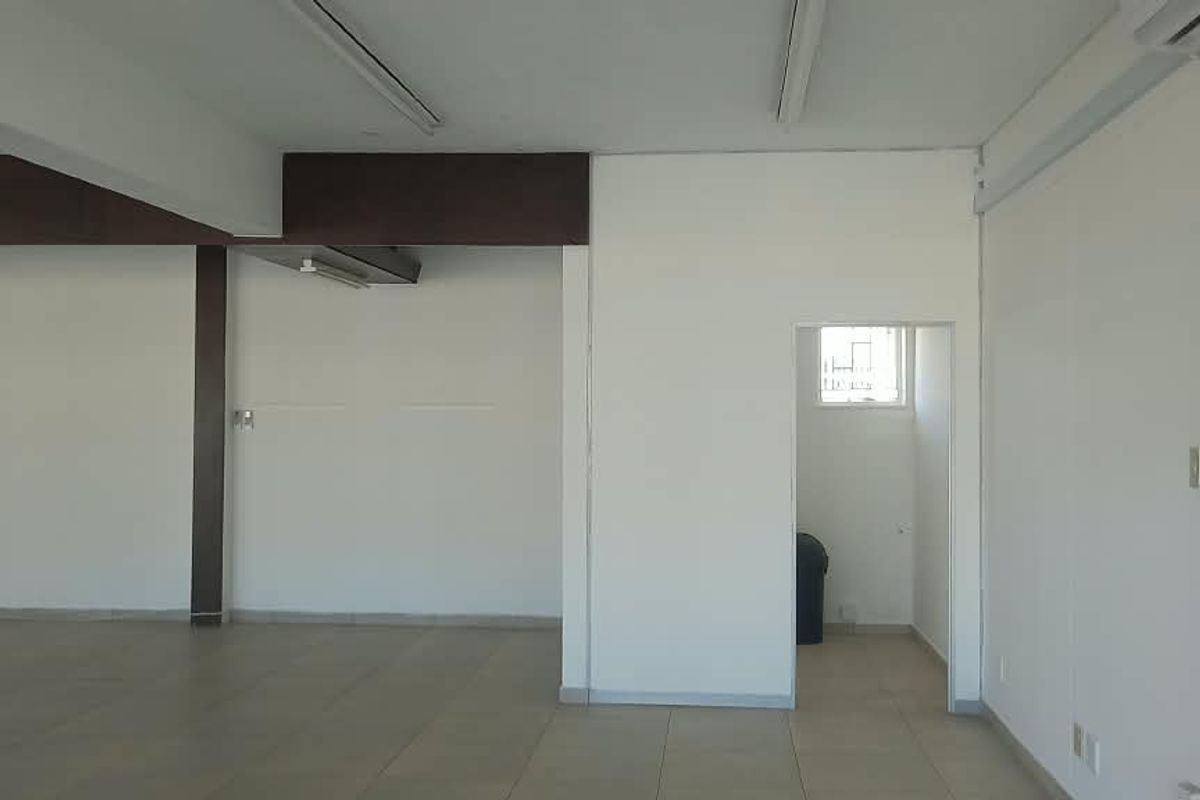 A spacious, empty open-plan retail area featuring tiled flooring, structural columns, and neutral white walls, suitable for various commercial business layouts.