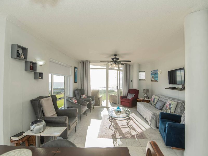 Spacious living room featuring tiled flooring, a ceiling fan, and large sliding glass doors that provide natural light and access to the outdoor area.