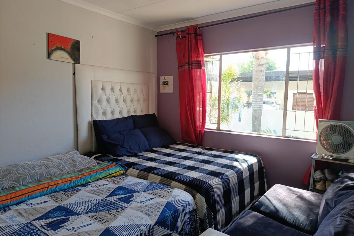 A bedroom featuring a large window with security burglar bars and decorative coving, providing natural light and a view of the exterior.