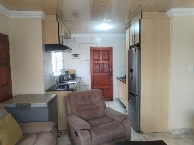 A functional kitchen featuring built-in cabinetry, tiled backsplash, and a timber ceiling, offering a practical layout with integrated cooking appliances.