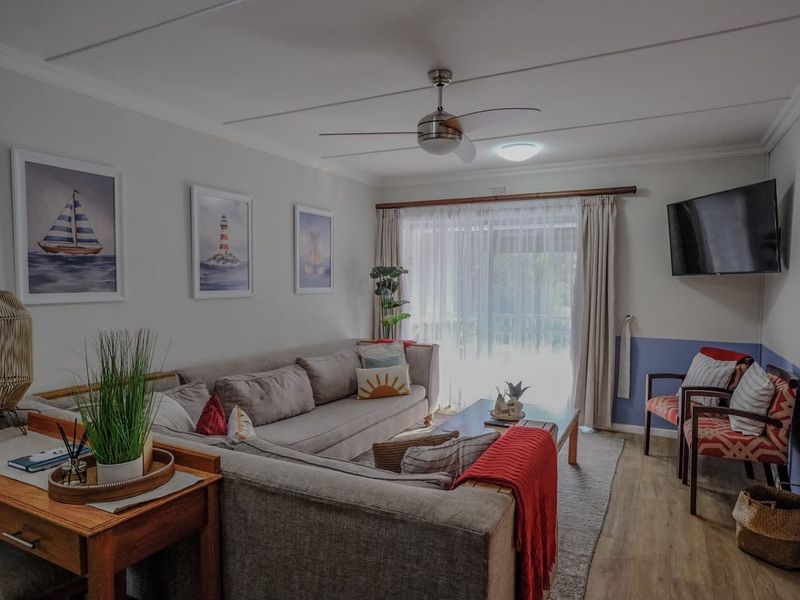 A comfortable living room featuring laminate flooring, a ceiling fan, and a sliding glass door that provides access to the outdoor area.