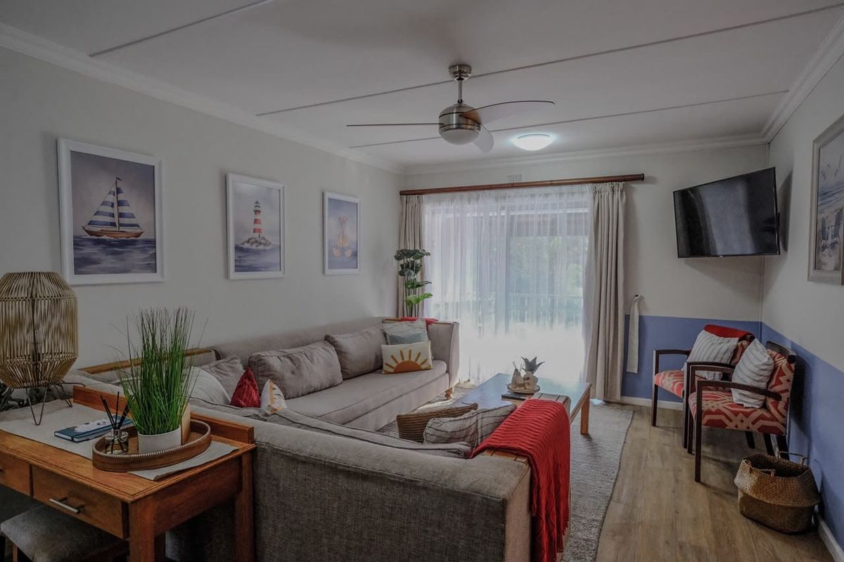 A comfortable living room featuring laminate flooring, a ceiling fan, and a sliding glass door that provides access to the outdoor area.