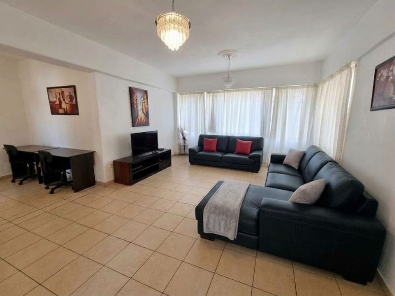Spacious living room featuring neutral tiled flooring, decorative ceiling roses, and elegant crystal chandeliers, offering a bright and functional layout.