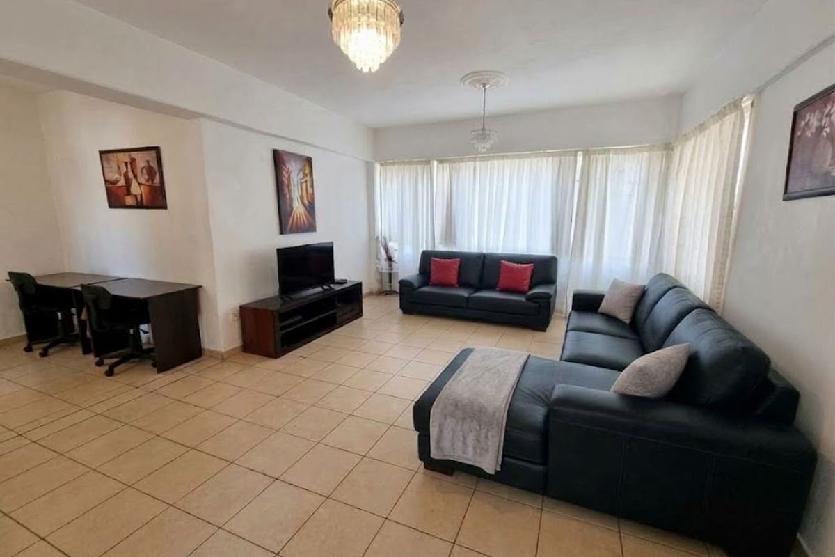 Spacious living room featuring neutral tiled flooring, decorative ceiling roses, and elegant crystal chandeliers, offering a bright and functional layout.