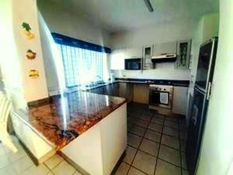 A functional kitchen featuring built-in cabinetry, laminate countertops, a built-in oven with extractor fan, and tiled flooring.